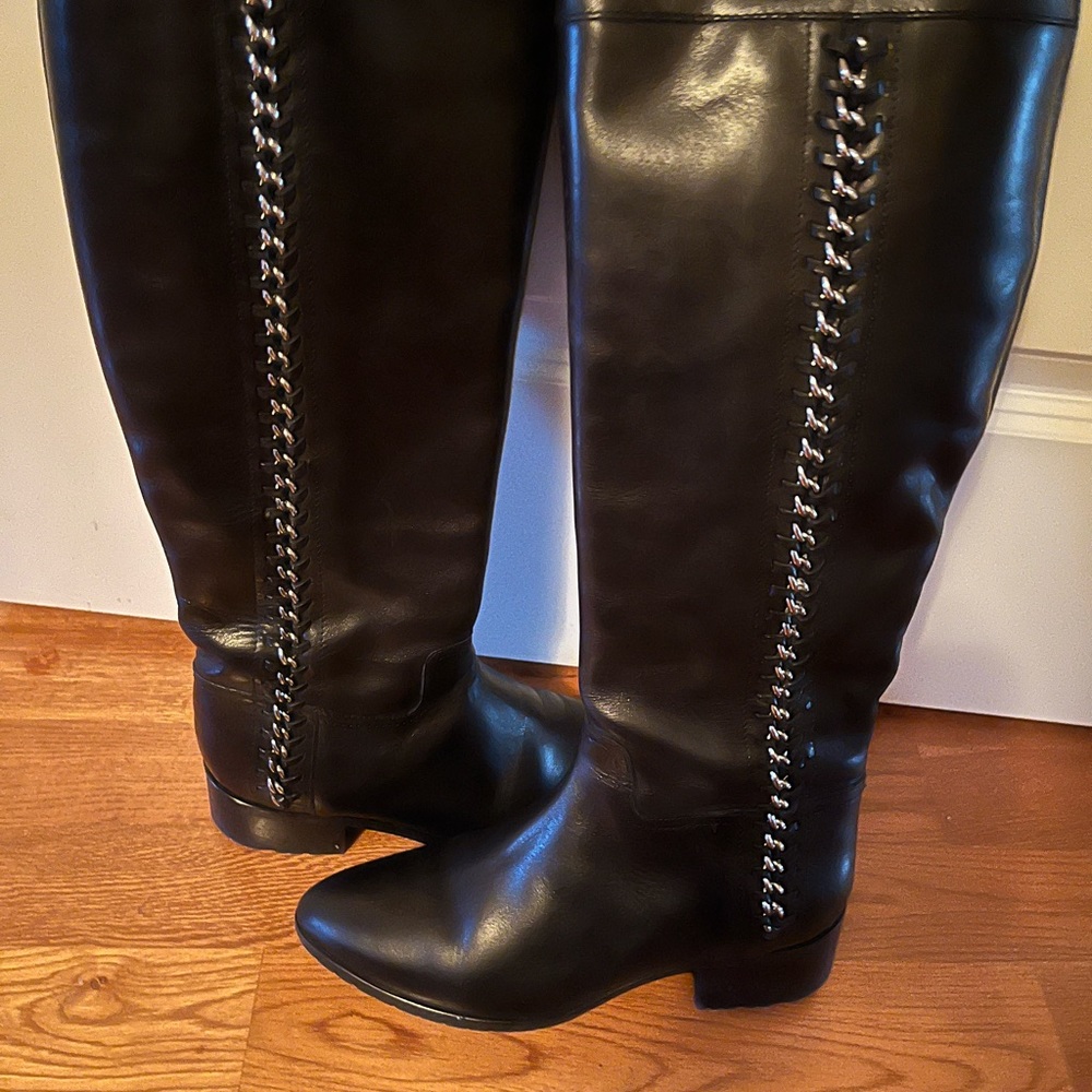 Black leather knee high boots with silver chain and side zipper.
